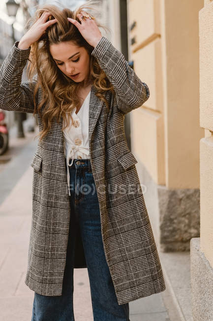Елегантна молода жінка стоїть на вулиці з руками в волоссі — стокове фото