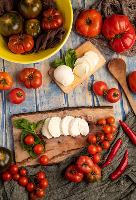 Frische Tomaten und Mozzarella mit Basilikumblättern für Salat auf Holzbrett und Stoff — Stockfoto