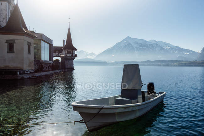 Small boat docked at suburban harbour on background of snow covered mountain and clear sky — Stock Photo