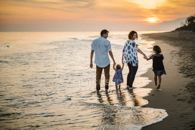Familia caminando en la playa - foto de stock