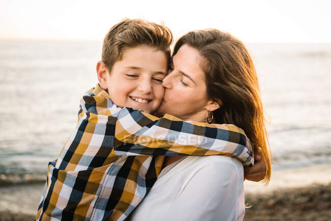 Middle aged woman with her son at sea shore smiling and hugging each other — Stock Photo