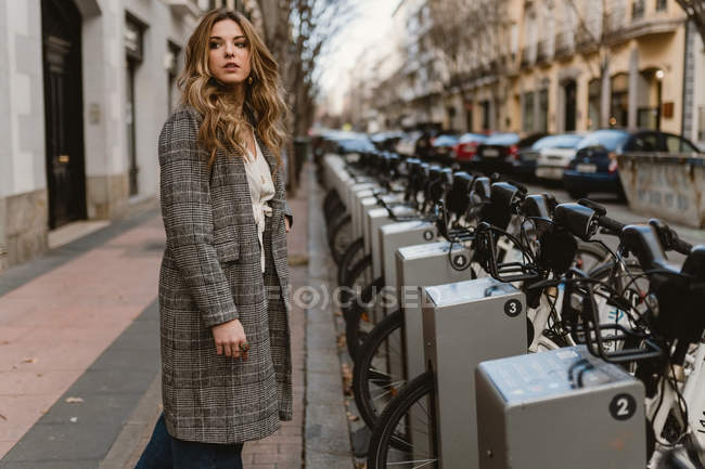 Señora elegir la bicicleta de alquiler en el estacionamiento - foto de stock