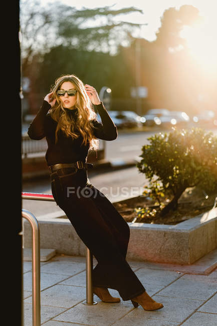 Mulher elegante de pé perto da estação de metro na rua ensolarada — Fotografia de Stock