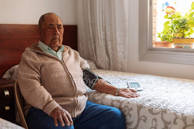Anciano comprobando su presión arterial con la máquina - foto de stock