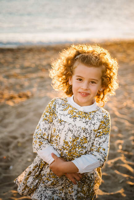 Retrato de menina bonito em vestido no litoral da praia sob uma bela luz do pôr do sol — Fotografia de Stock