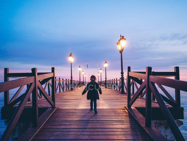 Вид ззаду анонімної дівчини на пляжний пірс вночі — стокове фото