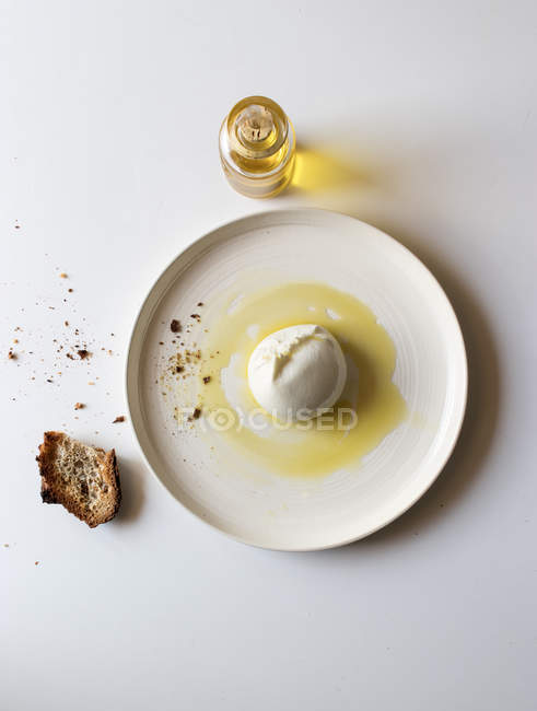 Prato com burrata saborosa e pedaço de pão com óleo sobre fundo branco — Fotografia de Stock