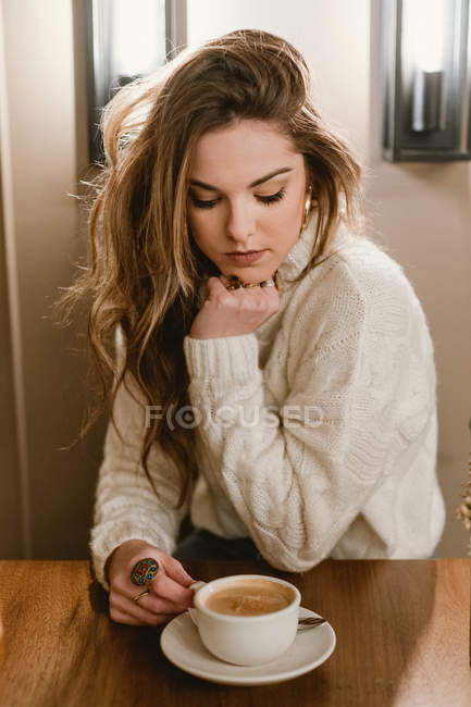 Elegant woman mixing coffee in cafe — Stock Photo