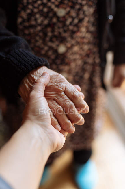 Nieto sosteniendo la mano de su abuela - foto de stock