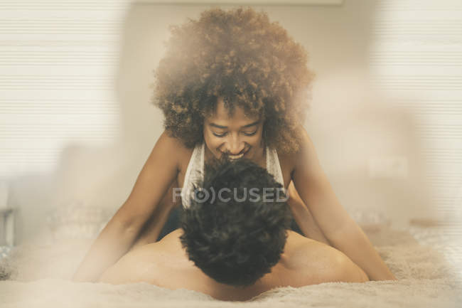 Joven sensual hombre y mujer acostado en la cama y abrazos en la acogedora habitación en casa - foto de stock
