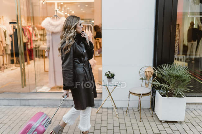 Elegante donna con valigia che cammina per strada — Foto stock