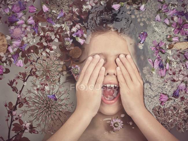 Dall'alto faccia di bambino in liquido tra petali freschi di fioriture — Foto stock