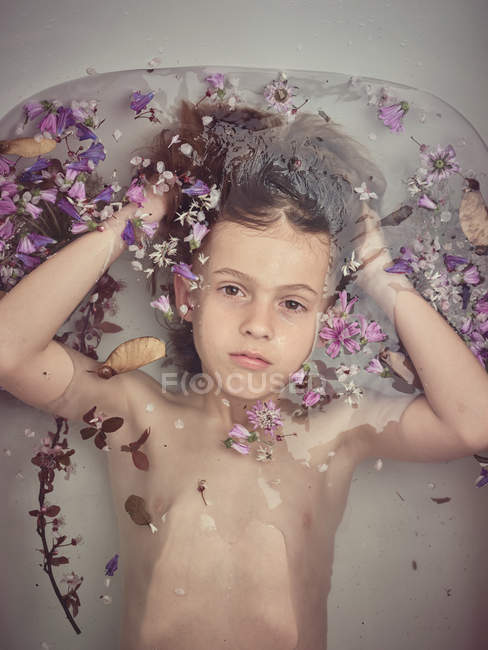 Von oben Kindergesicht in Flüssigkeit zwischen frischen Blütenblättern — Stockfoto