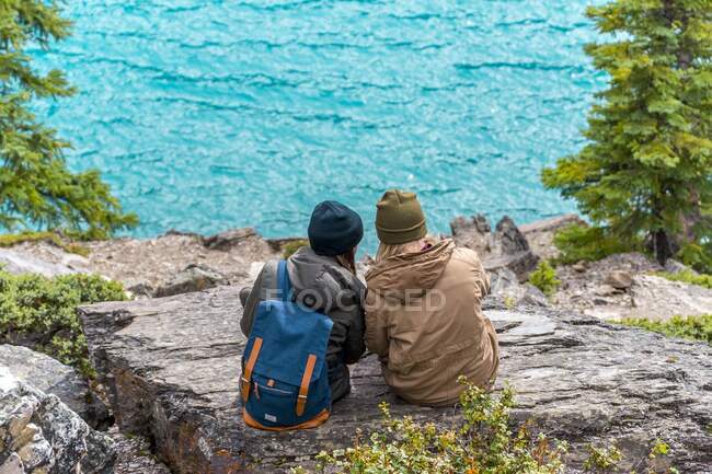 Persons sitting on stones near amazing lake — Photo de stock