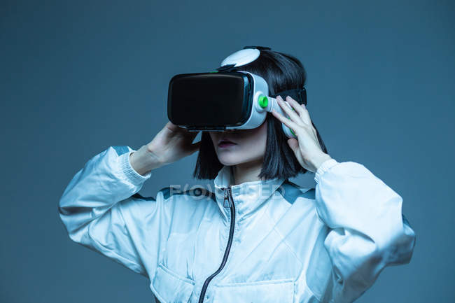 Mujer joven emocionada teniendo experiencia de realidad virtual en luz de neón - foto de stock