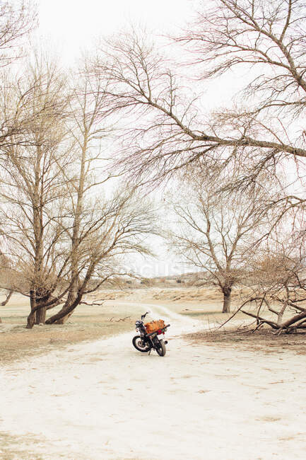 Moto située sur une route de campagne étroite dans un champ sec pendant le voyage dans la nature — Photo de stock