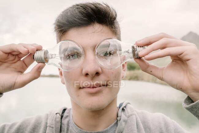 Jovem adolescente com um par de lâmpadas na frente de seus olhos inovação e imaginação conceito — Fotografia de Stock
