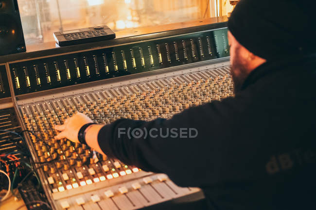 Vue arrière de l'homme travaillant en jouant dans un instrument égaliseur dans un studio — Photo de stock