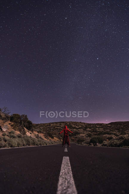 Путешественник, стоящий ночью на пустой дороге — стоковое фото