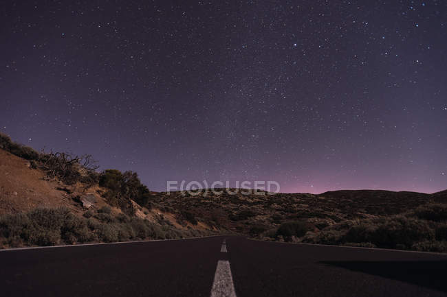 Malerischer Blick auf die Fahrbahn in der spanischen Wüste vor atemberaubendem dunklen Himmel mit leuchtenden Sternen — Stockfoto