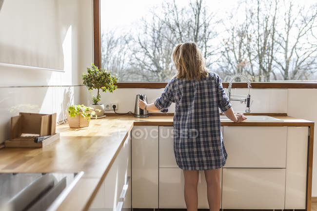 Schöne junge Frau in der Küche ihres Hauses — Stockfoto