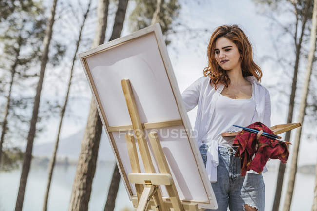 Jeune femme peignant à la campagne — Photo de stock