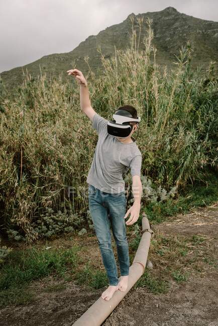 Jovem adolescente jogando uma simulação de realidade virtual com óculos vr e balanceamento em um tubo de tubo — Fotografia de Stock