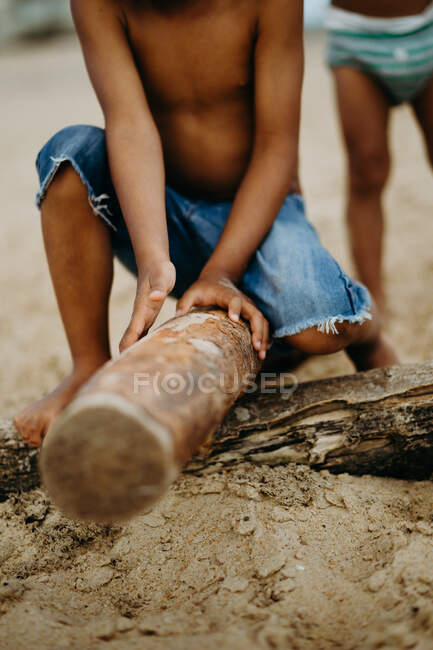 Afrikanischer Junge mit Stock spielt am Sandstrand in der Nähe des Meeres — Stockfoto