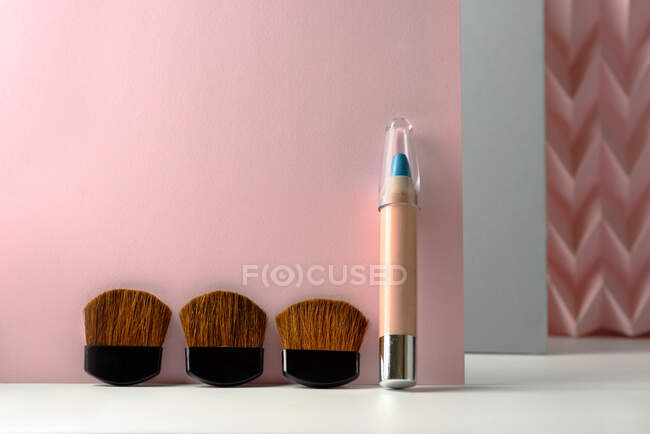 Lápices cosméticos:, maquillaje lápiz delineador de ojos azul, fondo moderno con relieves de color rosa chevron. inventar el concepto - foto de stock