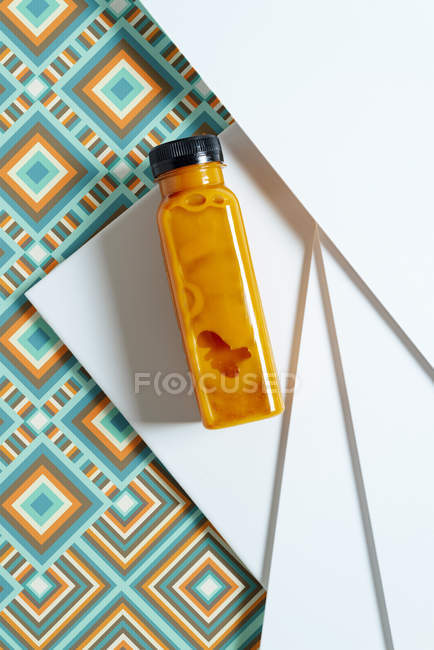 Mango and pumpkin smoothie bottle over retro style geometric texture — Stock Photo