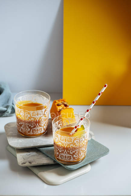 Bicchieri di frullato di mango e zucca su assi impilate — Foto stock