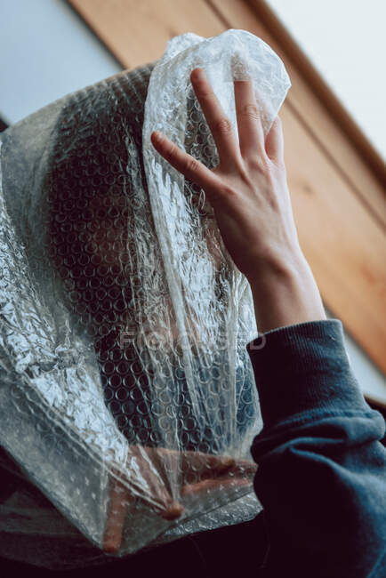 Scared woman trying to free herself while entangled in bubble wrap — Stock Photo
