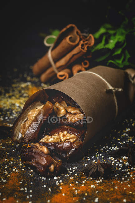Dried dates, figs, fresh mint and cinnamon for halal snack for Ramadan wrapped in parchment on dark background — Stock Photo