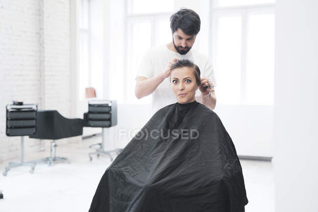 Cabeleireiro corta o cabelo da mulher com tesoura — Fotografia de Stock