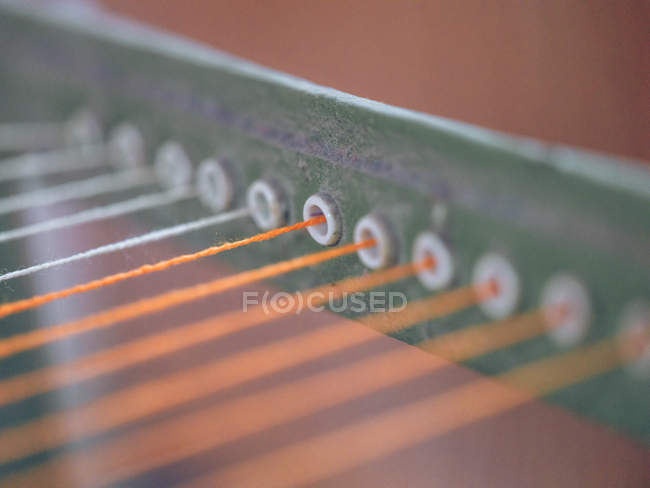 Close-up de fios brancos e laranja no tear — Fotografia de Stock