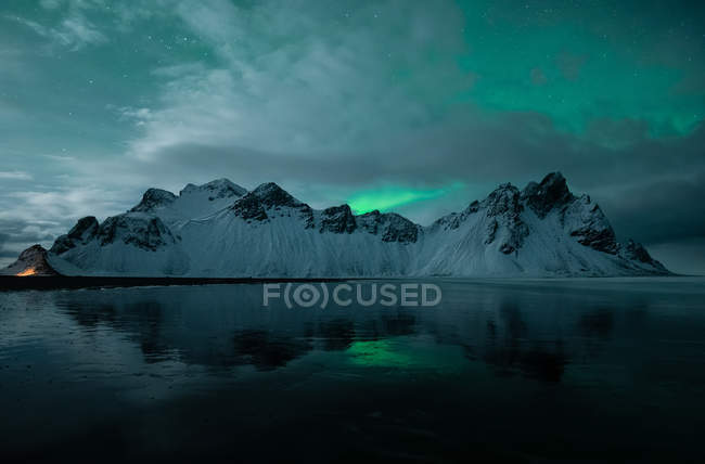 Blick auf die schneebedeckten Klippen unter Nordlicht im stockfinsteren Island — Stockfoto