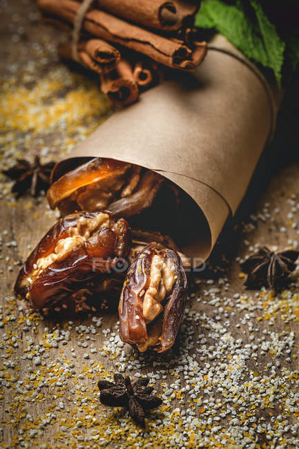 Dried dates, figs, fresh mint and cinnamon for halal snack for Ramadan wrapped in parchment on dark background — Stock Photo