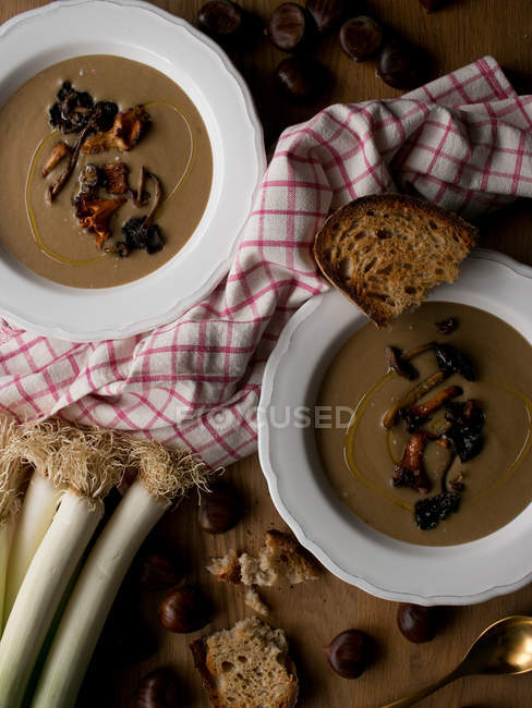 Teller mit köstlicher Kastaniensuppe mit Pilzen und Serviette auf Holztischplatte. — Stockfoto