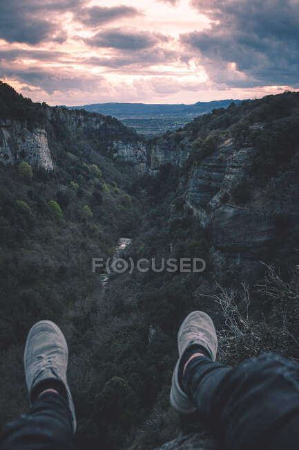 Vue sur la petite rivière dans le canyon et les jambes de la personne assise sur le bord — Photo de stock