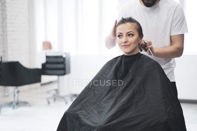 Coiffeur coupe les cheveux de la femme avec des ciseaux — Photo de stock