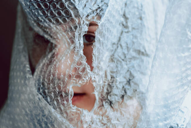 Woman looking at the camera while entangled in bubble wrap — Stock Photo
