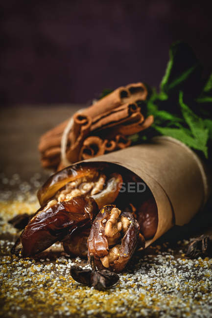 Dátiles secos, higos, menta fresca y canela para merienda halal para Ramadán envuelto en pergamino sobre fondo oscuro - foto de stock