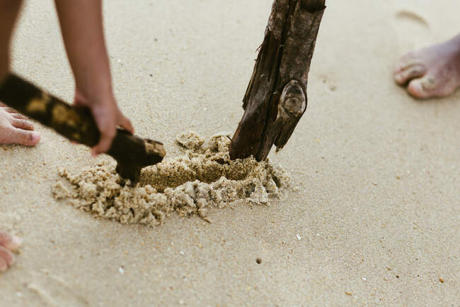 Афроамериканский мальчик с палкой играет на песчаном берегу у моря — стоковое фото