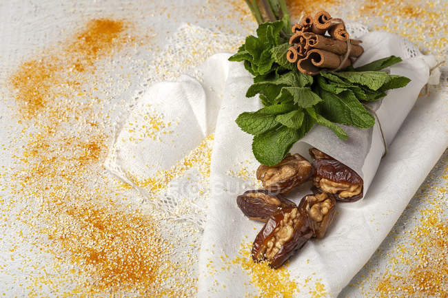 Datteri secchi, fichi, menta fresca e cannella per merenda halal su panno bianco con spezie — Foto stock