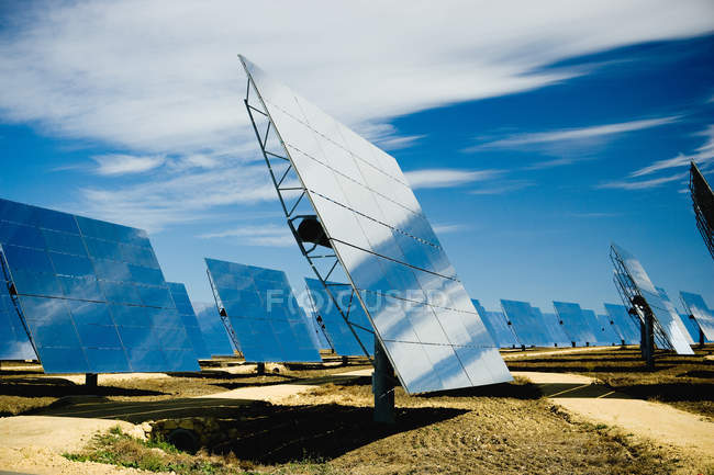 Сонячні панелі на електростанції під блакитним небом з хмарами — стокове фото