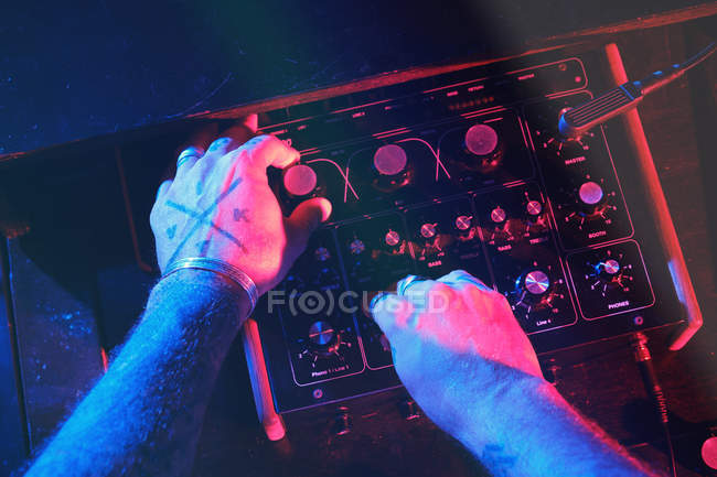 Hände eines anonymen DJ-Mannes, der in einem Club mit Lichtern spielt — Stockfoto