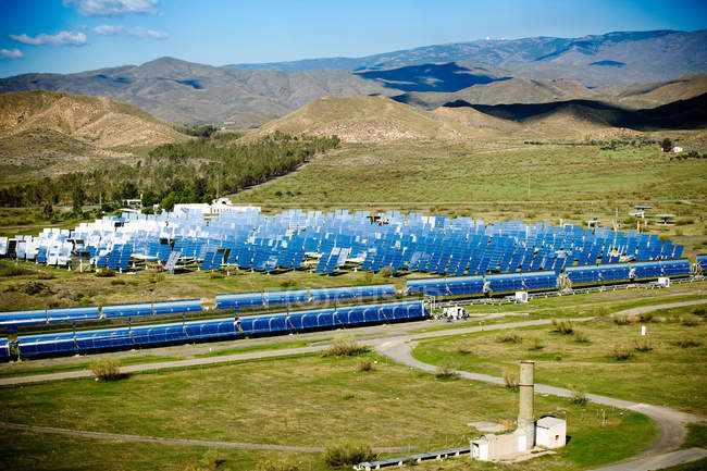 Paneles solares en la central eléctrica en el campo con montañas en el fondo - foto de stock