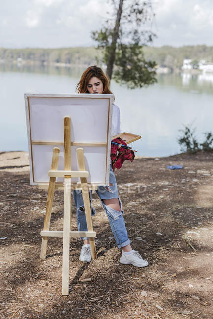 Mujer joven pintando en el campo - foto de stock