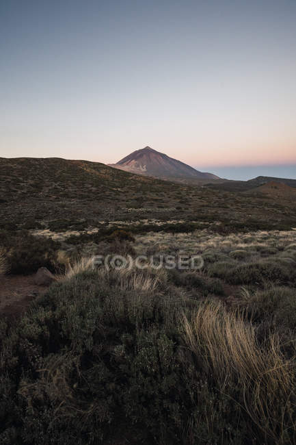 Pico de montaña en el valle del desierto al atardecer - foto de stock