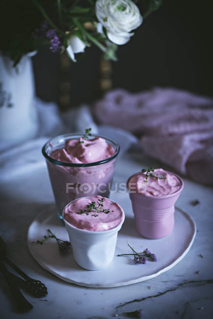 Copos de mousse de morango doce na mesa com flores — Fotografia de Stock